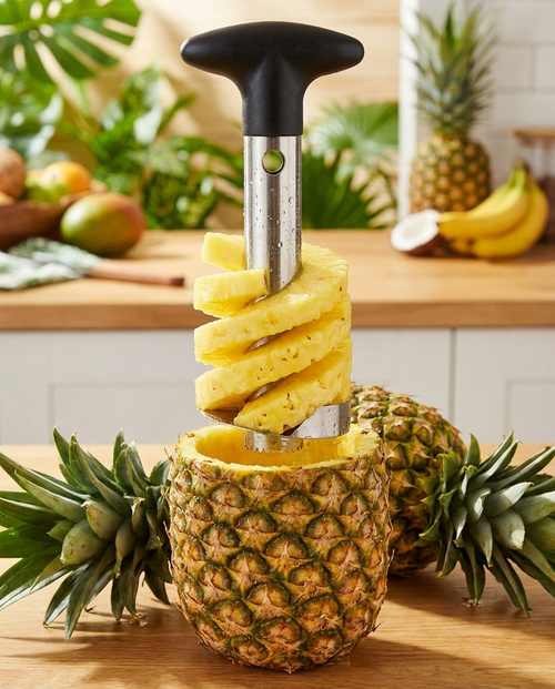 Stainless steel pineapple corer lifting a spiral of fresh pineapple